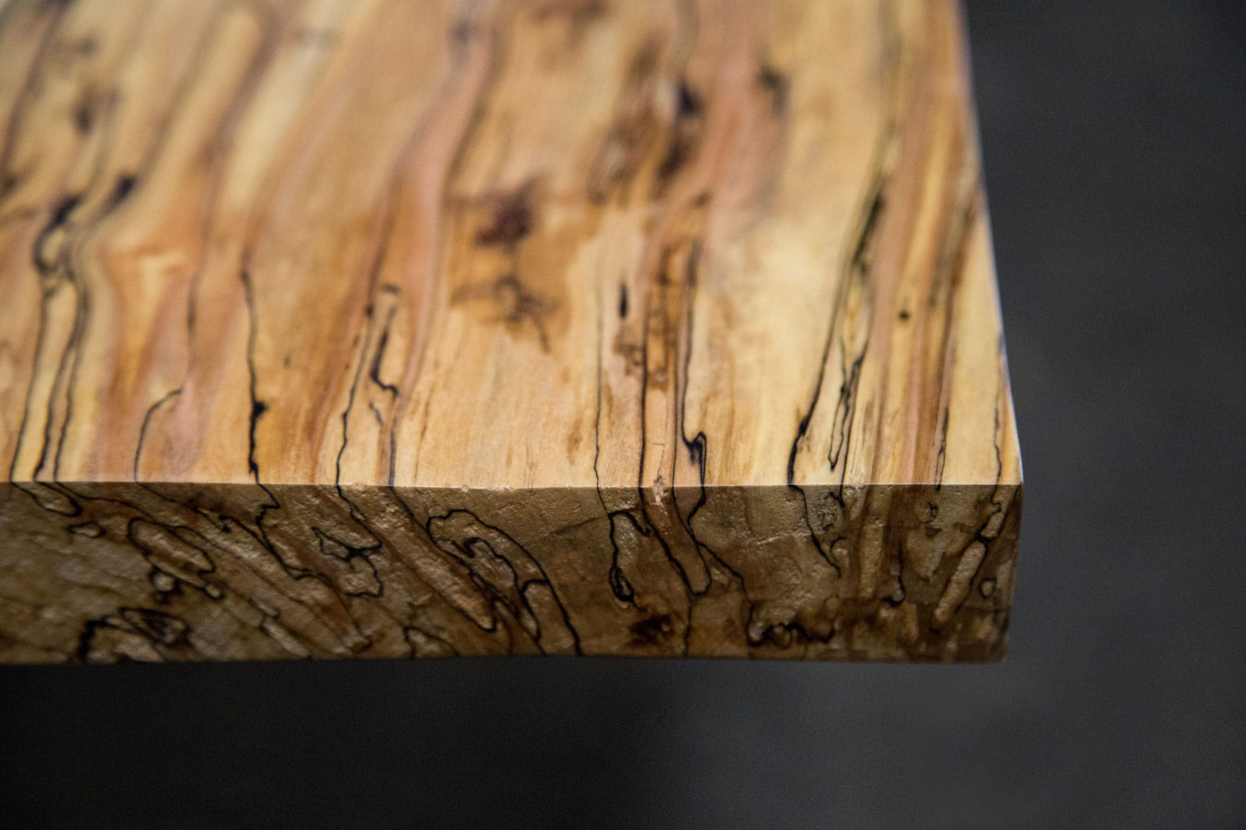 Angled view of a high-character live edge Colorado table crafted from ambrosia maple with unique natural details.