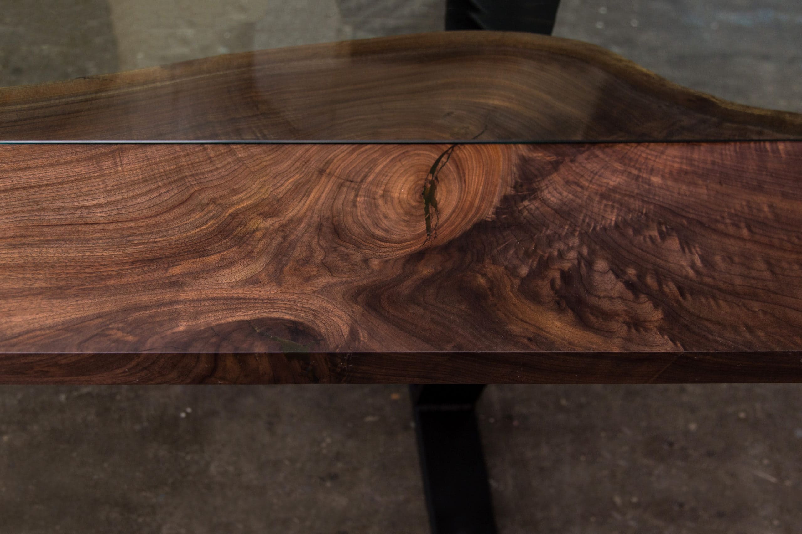 A detailed close-up of the butterfly base design of a live edge black walnut Colorado table, showcasing its craftsmanship.