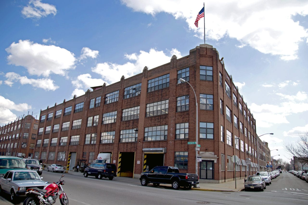 an outside corner street view of SENTIENT red brick office building with American flag waving on top