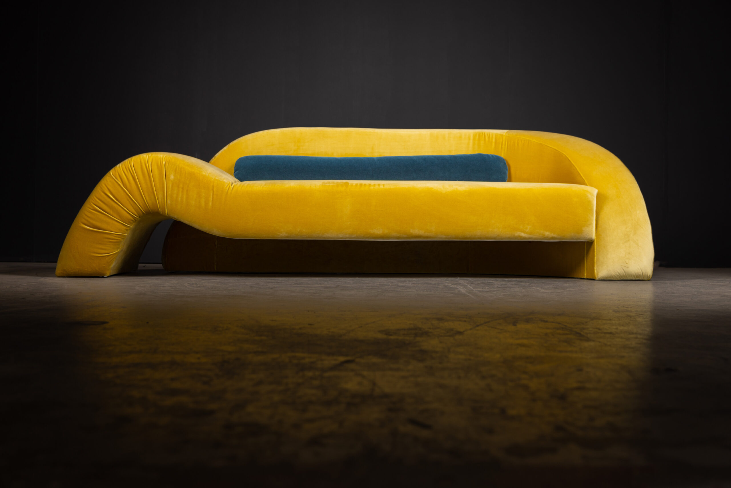 Sentient Aeon Sofa in Yellow Velvet (Front View) A front view of the Sentient Aeon Sofa in bright yellow velvet, paired with a contrasting blue pillow, perfect for contemporary interiors.