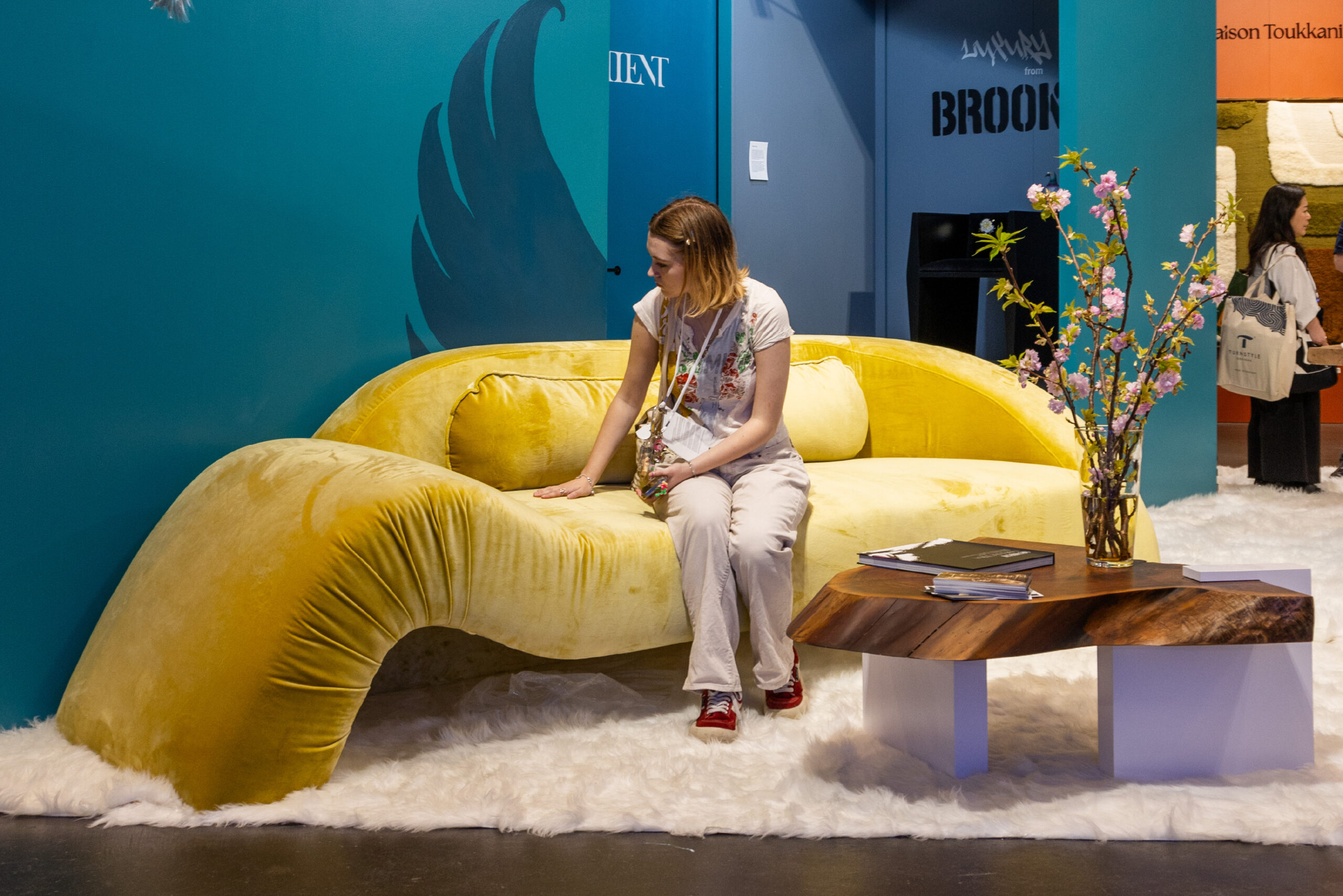 Sentient Booth with Aeon Sofa in Yellow Velvet at ICFF 2024 The Sentient booth at ICFF 2024, featuring the Aeon Sofa in yellow velvet, accompanied by natural wood accents and modern decor.
