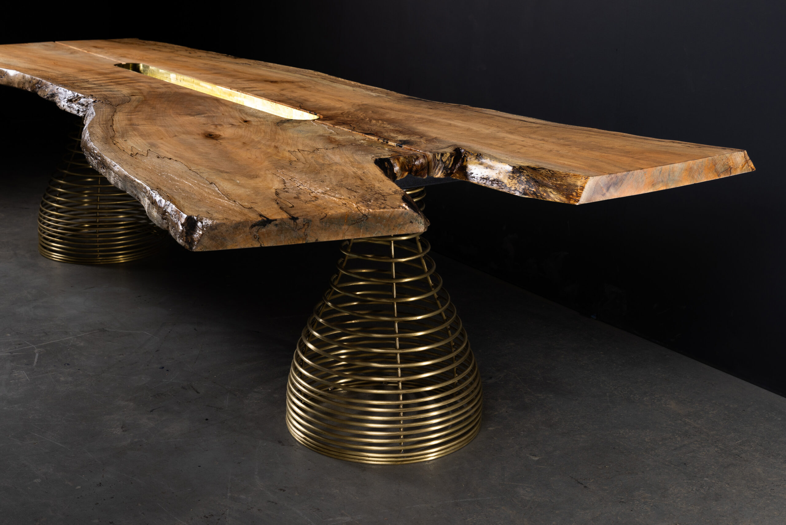 SENTIENT Rivulet Table in Live Edge Splatted Maple Angle View An angled view of the SENTIENT Rivulet Table, highlighting the elegant curve and live edge design of the splatted maple top paired with brass spring legs.