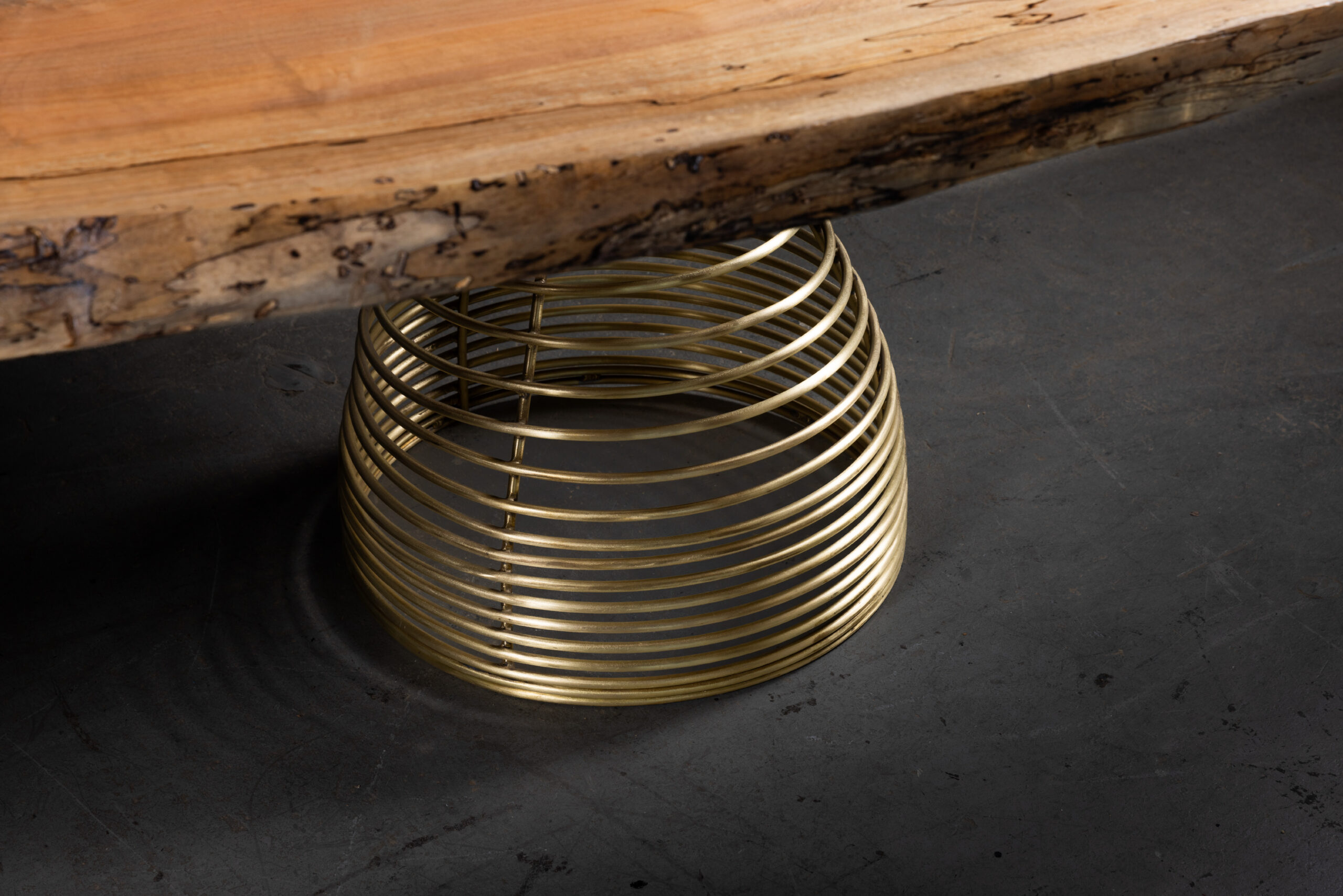 SENTIENT Rivulet Table in Live Edge Splatted Maple Spring Brass Legs Details A closeup view focusing on the brass spring legs supporting the SENTIENT Rivulet Table, accentuating the balance between organic wood and metallic elements.