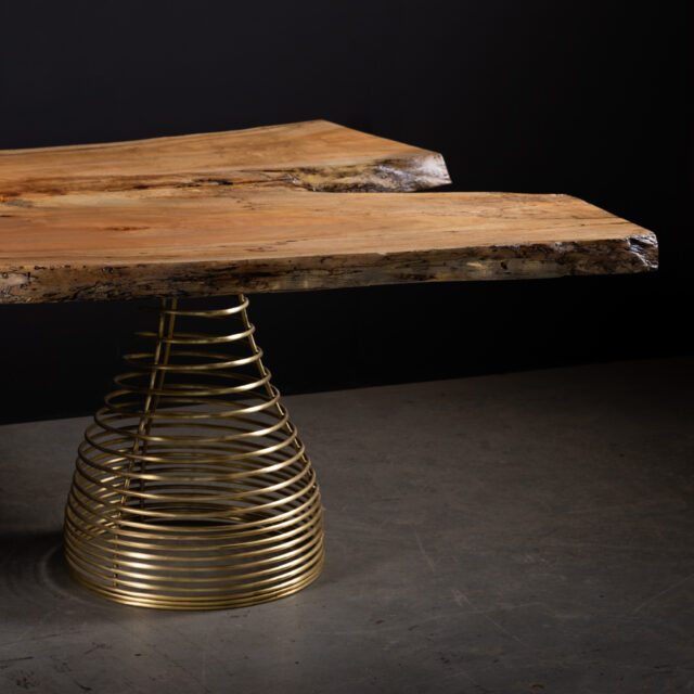 The SENTIENT Rivulet Table featuring a live edge spalted maple top paired with a striking brass spiral base. This unique design combines natural wood beauty with a bold, sculptural aesthetic.