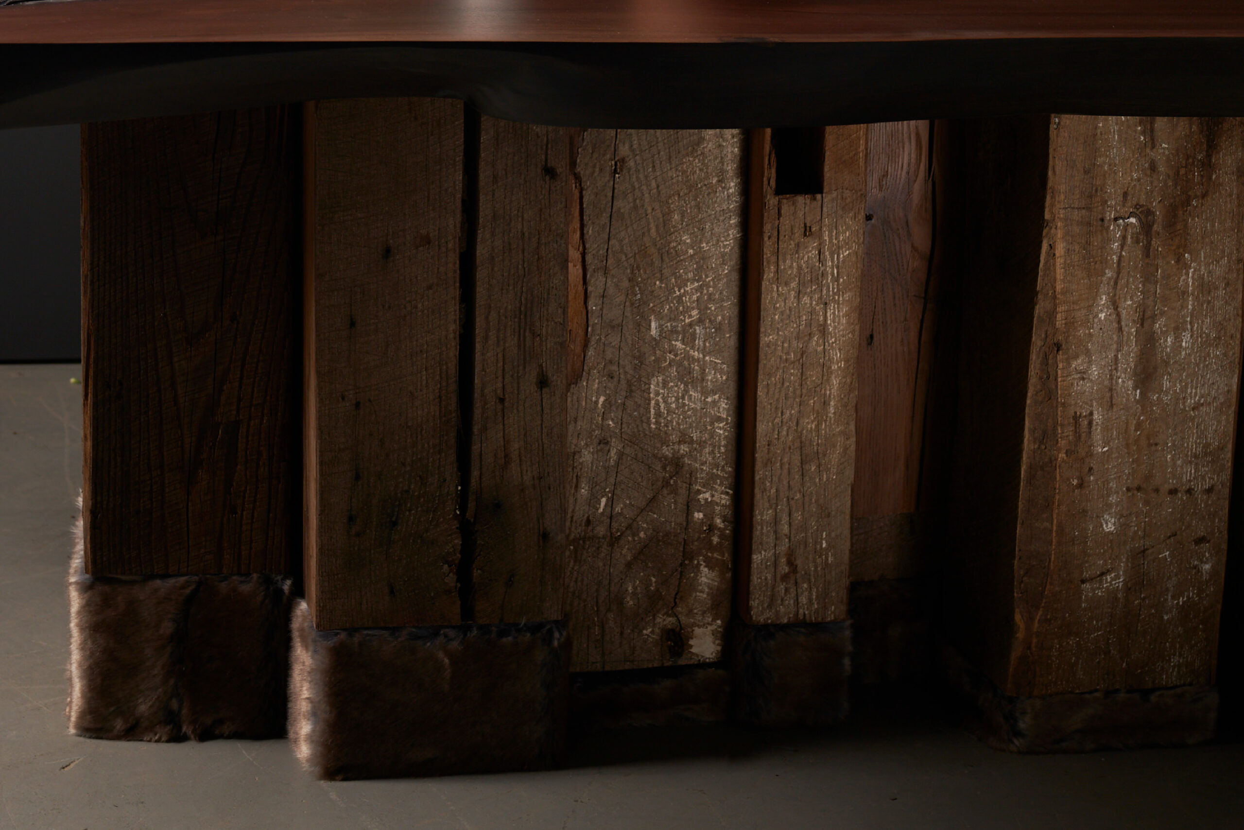 SENTIENT Evolution Artistic Live Edge Table - Base Details A close-up view of the base of the SENTIENT Evolution table, featuring rustic wooden legs with a natural finish.