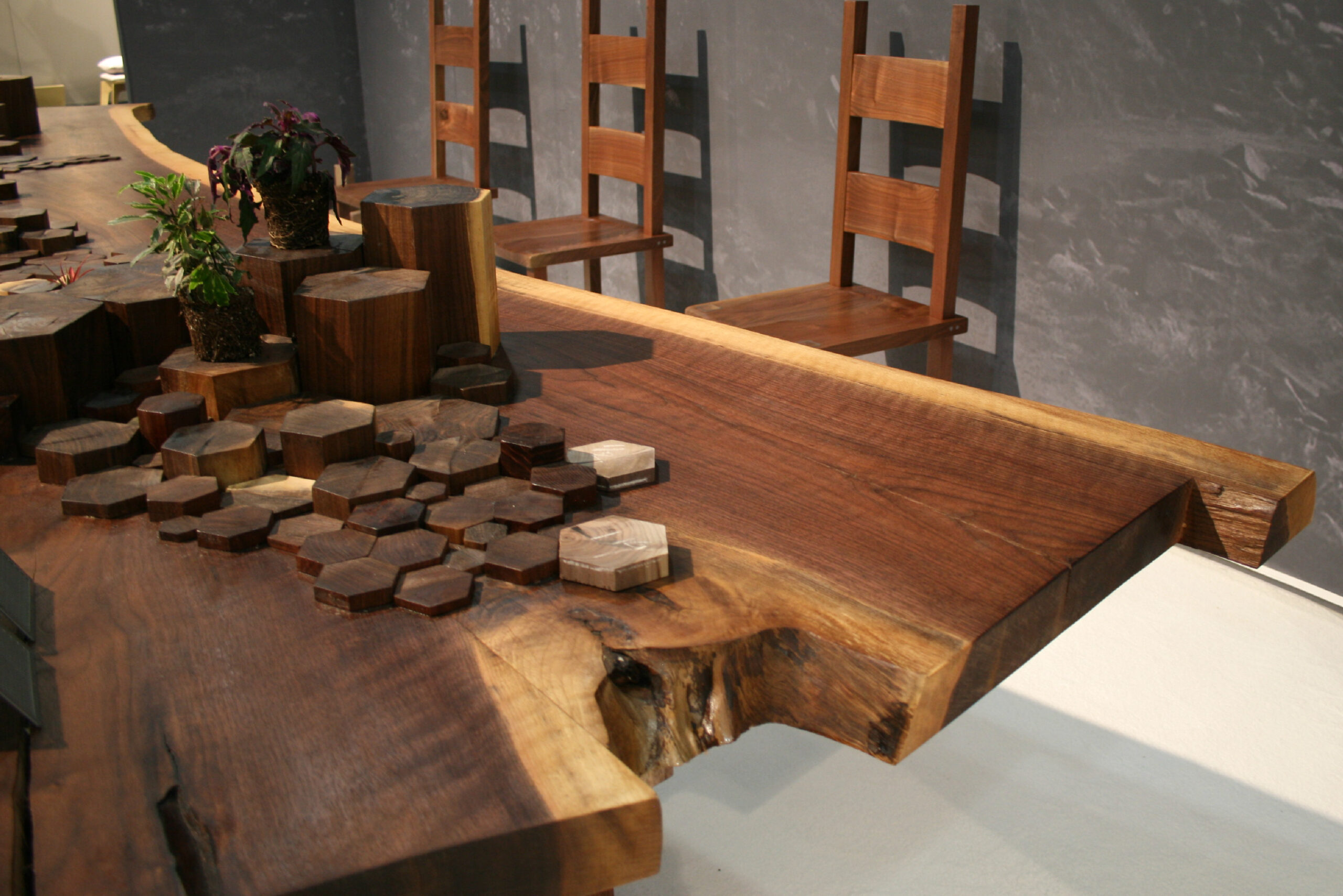 SENTIENT Causeway Table Details at ICFF Detailed shot of the SENTIENT Causeway Table's surface at ICFF, showing layered wooden hexagons and plant decor inspired by rock formations.